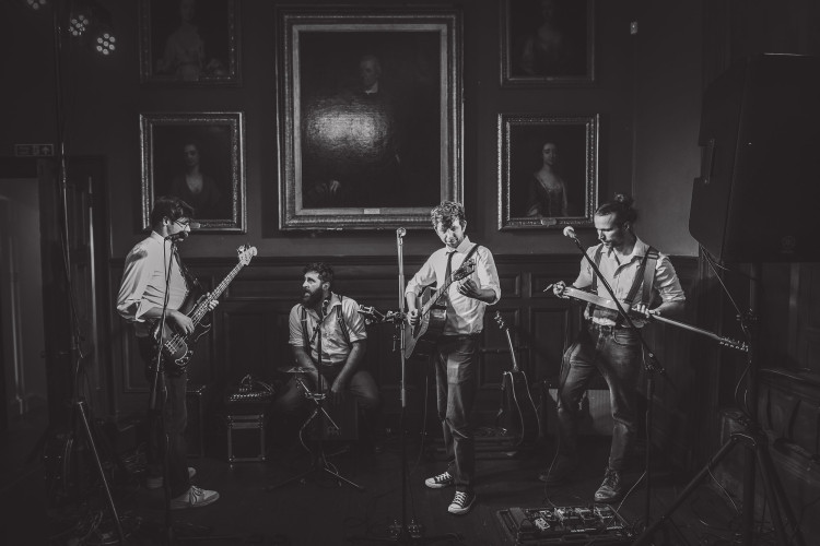 Buskers & Sons wedding band four piece performing in a portrait hall