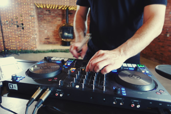 Live Band vs DJ - Man Adjusting the Faders on a Set of DJ Decks